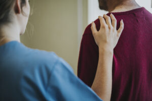 Asociatyvi nuotrauka, slaugytoja uždėjusi ranką ant paciento peties